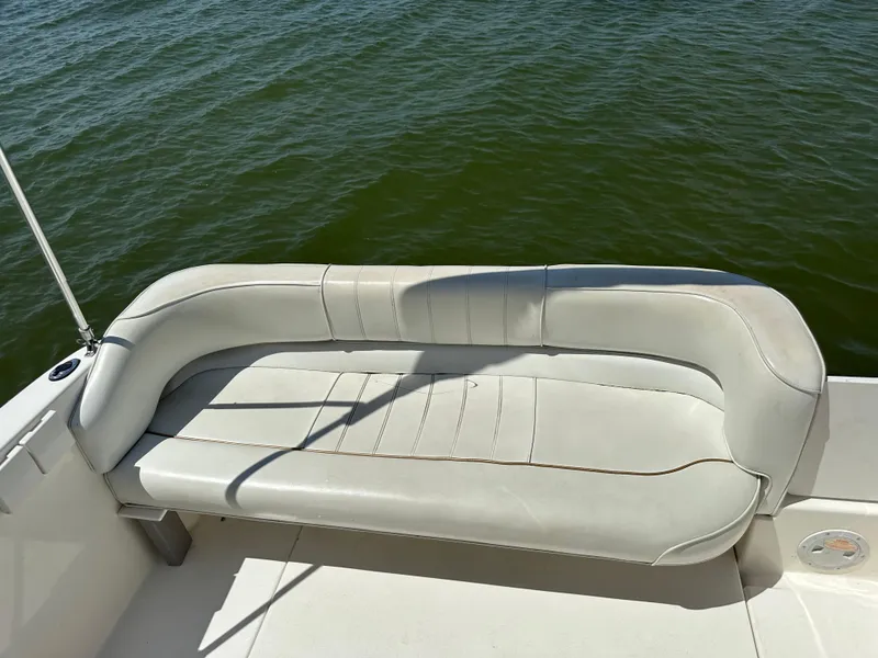 Slide: The Image of 1998 Sea Ray 240 Sundancer boat seat with white upholstery, overlooking calm green water. - 18