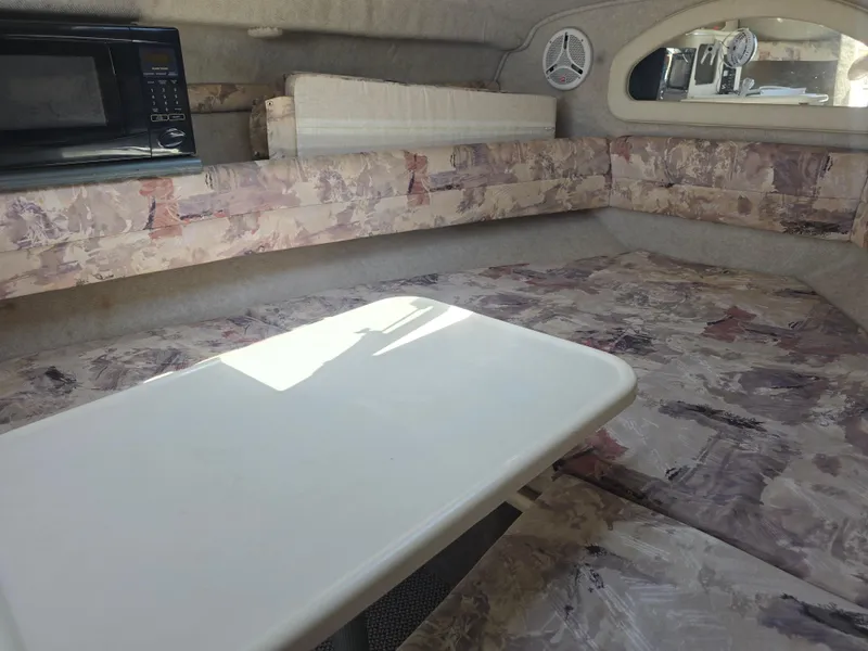 Slide: The Image of 1998 Sea Ray 240 Sundancer cabin interior with table, seating, and microwave. - 24