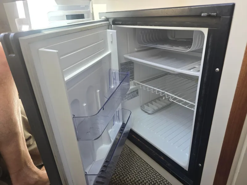 Slide: The Image of Open refrigerator inside a 1998 Sea Ray 240 Sundancer boat, showing shelves and door storage. - 26