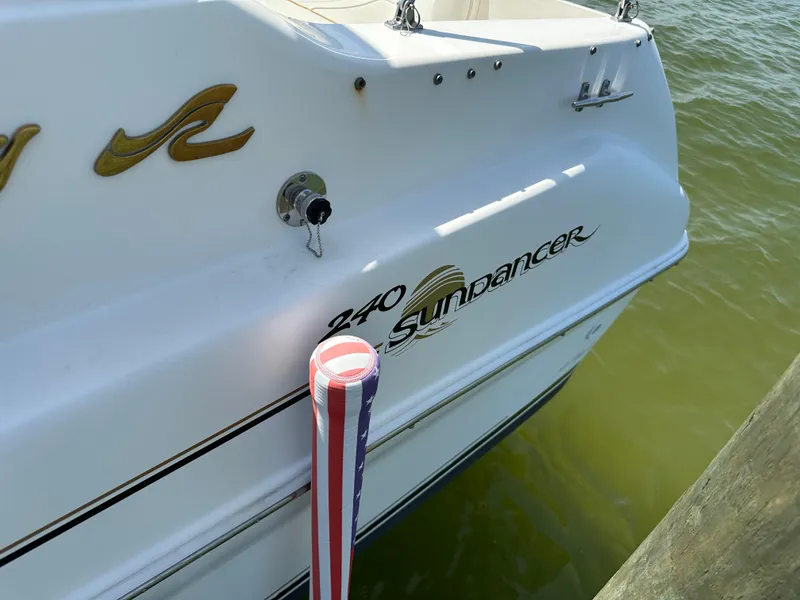 Slide: The Image of 1998 Sea Ray 240 Sundancer boat docked, featuring logo and patriotic fender. - 8