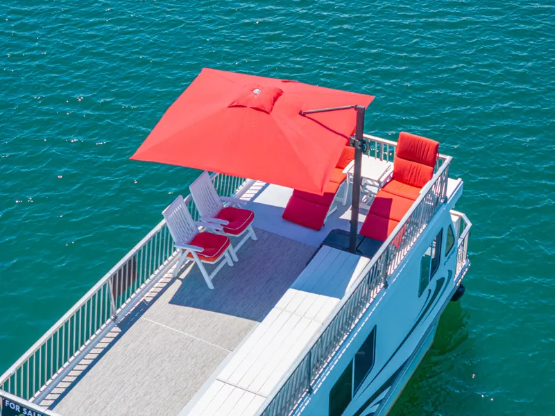 Slide: The Image of Houseboat with red umbrella and chairs on deck, Twin Anchors 3010, 2016 model, on blue water. - 10