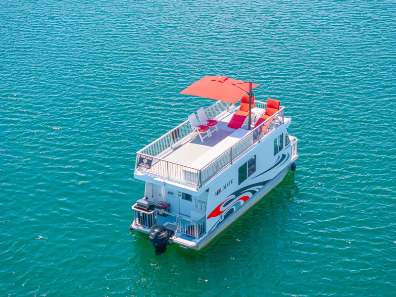 Slide: The Image of Houseboat on clear water, Twin Anchors 3010, 2016 model, with rooftop seating and umbrella. - 11