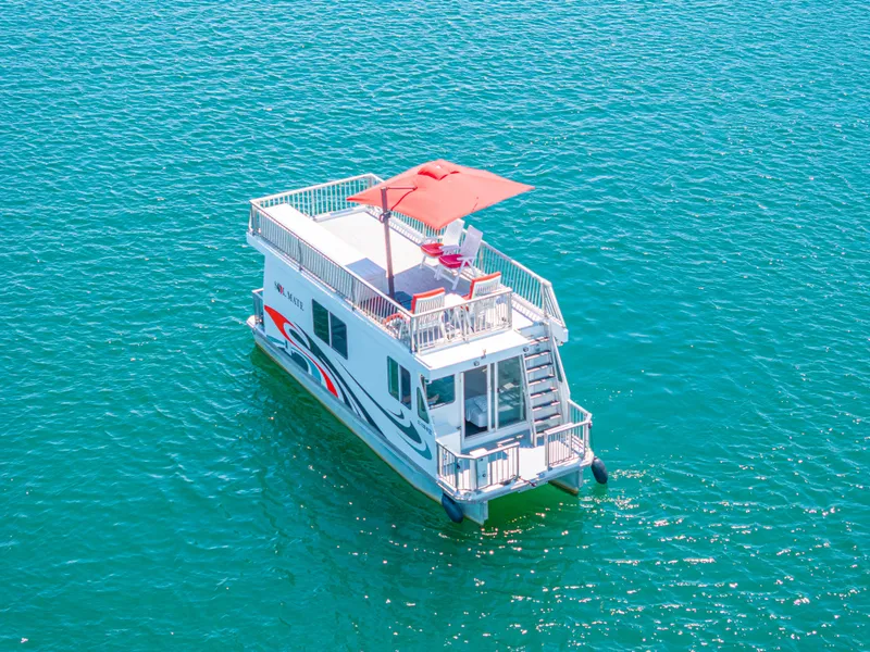 Slide: The Image of Houseboat on clear blue water, Twin Anchors 3010, 2016 model, with rooftop seating and umbrella. - 13