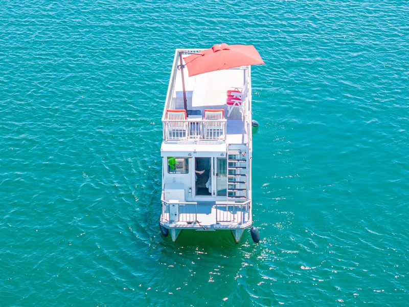 Slide: The Image of Aerial view of 2016 Twin Anchors 3010 houseboat with red umbrella on blue water. - 14