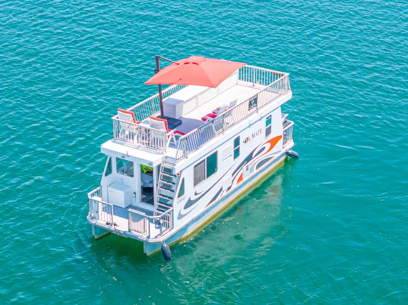 Slide: The Image of 2016 Twin Anchors 3010 houseboat with upper deck and red canopy on clear blue water. - 15