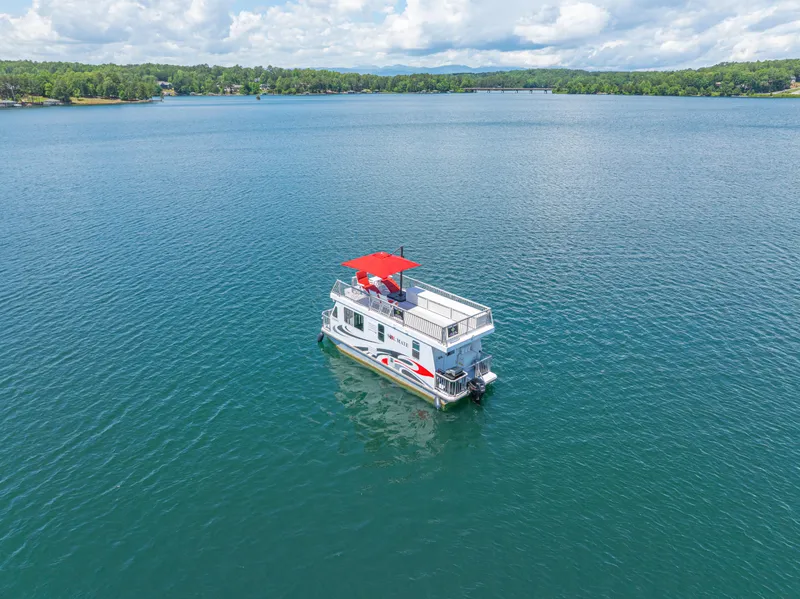Slide: The Image of Houseboat on a serene lake, Twin Anchors 3010, 2016 model, under a partly cloudy sky. - 2