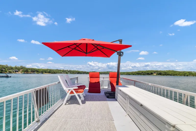 Slide: The Image of Houseboat deck with red umbrella, chairs, and scenic lake view under a clear blue sky. - 20