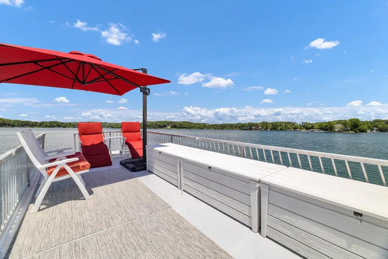 Slide: The Image of Upper deck of 2016 Twin Anchors 3010 houseboat with red umbrella and chairs, overlooking lake. - 21