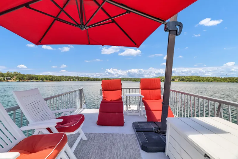 Slide: The Image of Upper deck of 2016 Twin Anchors 3010 houseboat with red loungers and umbrella. - 22