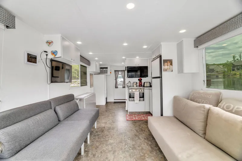 Slide: The Image of Modern 2016 Twin Anchors 3010 houseboat interior with cozy seating and kitchen area. - 24