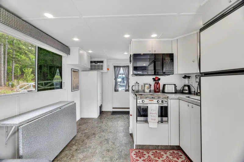 Slide: The Image of Interior of 2016 Twin Anchors 3010 houseboat kitchen with modern appliances and forest view. - 29