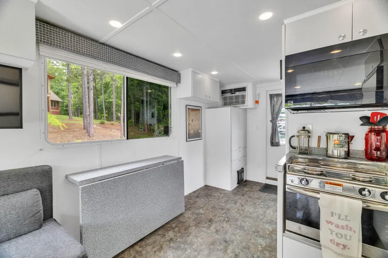 Slide: The Image of Modern 2016 Twin Anchors 3010 houseboat interior with kitchen, seating, and large windows. - 30