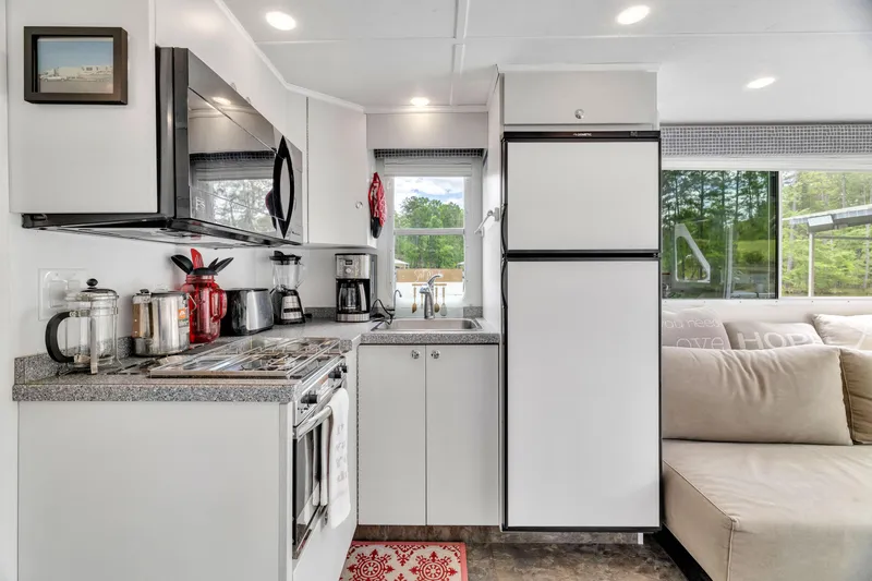Slide: The Image of Modern kitchen interior in a 2016 Twin Anchors 3010 houseboat, featuring appliances and cozy seating. - 33