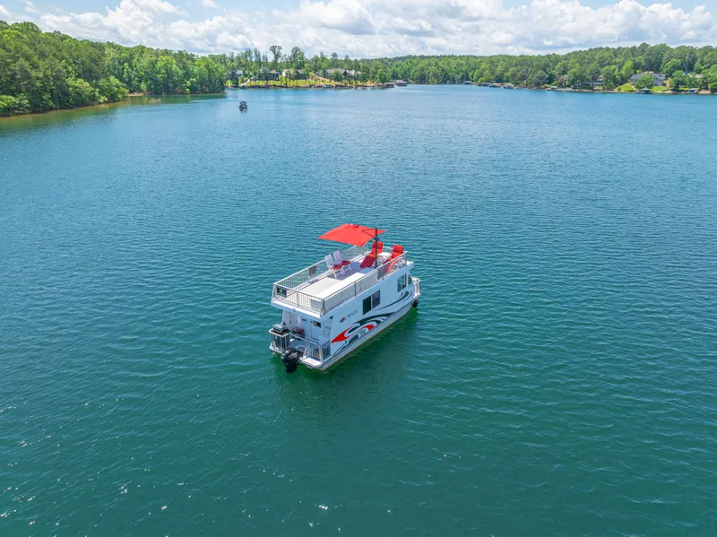 Slide: The Image of 2016 Twin Anchors 3010 houseboat on a serene lake with lush green shoreline. - 4
