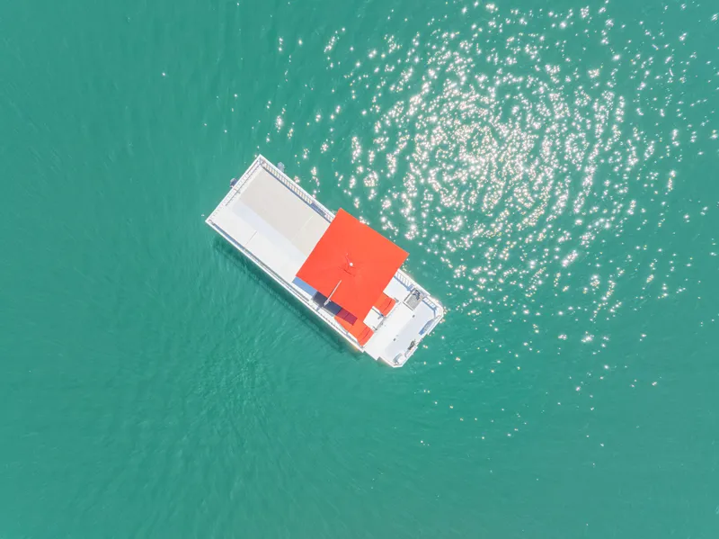 Slide: The Image of Aerial view of 2016 Twin Anchors 3010 houseboat with red roof on turquoise water. - 7