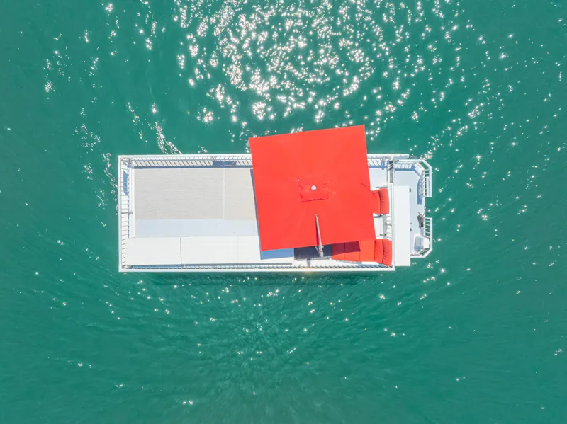 Slide: The Image of Aerial view of 2016 Twin Anchors 3010 houseboat with red roof on turquoise water. - 8