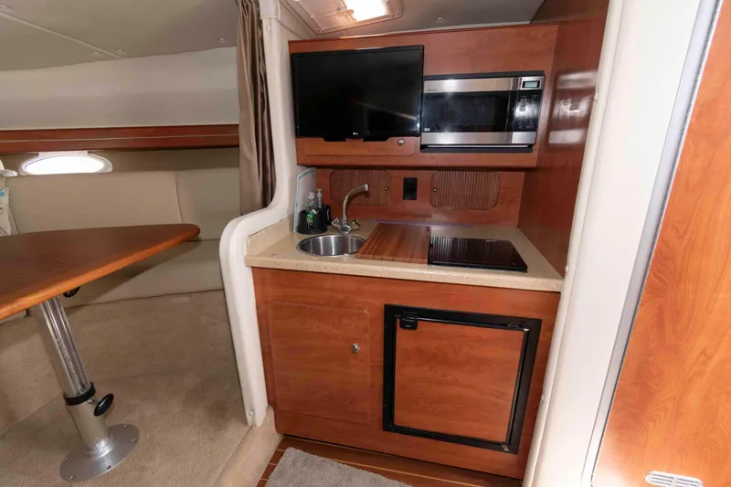 Slide: The Image of 2007 Rinker 300 Express Cruiser interior kitchen with sink, stove, microwave, and mini-fridge. - 14