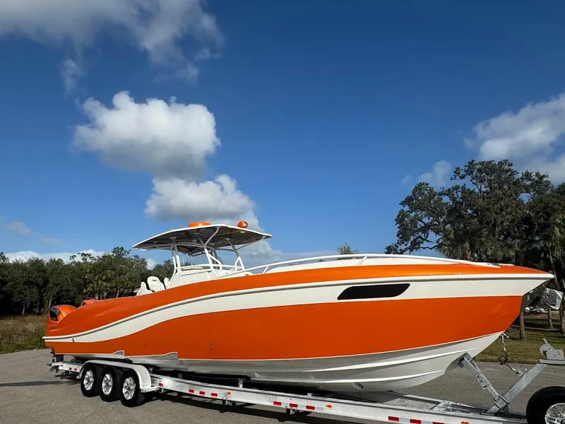 Slide: The Image of Orange 2015 Deep Impact 399 Cabin boat on trailer under blue sky. - 11