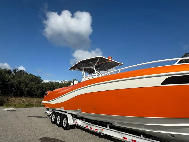Slide: The Image of Orange 2015 Deep Impact 399 Cabin boat on trailer under blue sky. - 12
