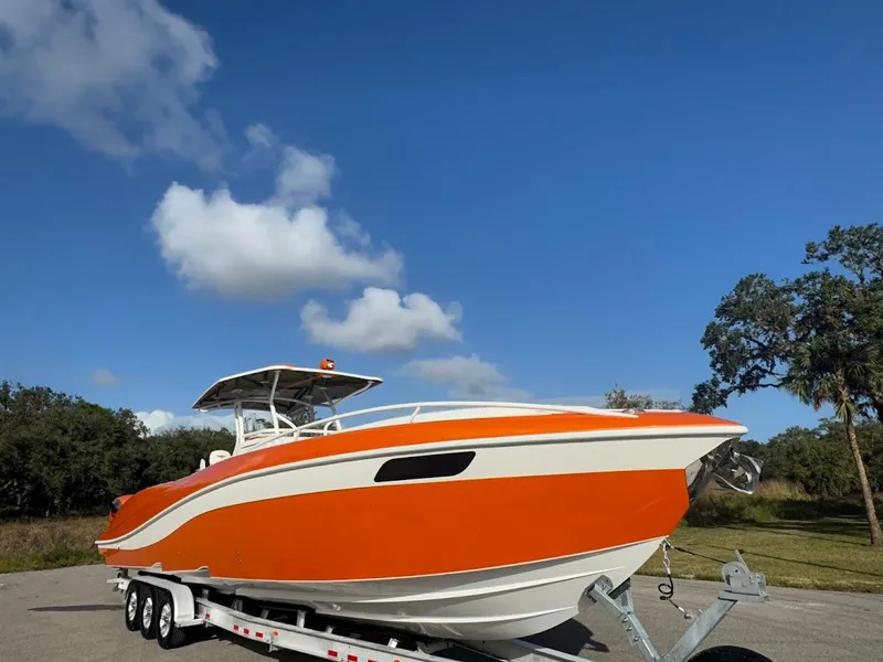 Slide: The Image of Orange 2015 Deep Impact 399 Cabin boat on trailer under blue sky. - 13