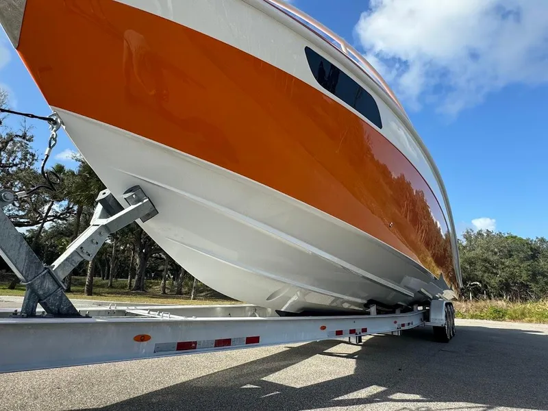 Slide: The Image of 2015 Deep Impact 399 Cabin boat on trailer, featuring vibrant orange and white design. - 14