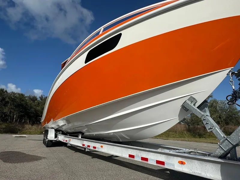 Slide: The Image of 2015 Deep Impact 399 Cabin boat with orange and white hull on a trailer. - 15