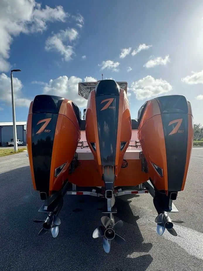 Slide: The Image of 2015 Deep Impact 399 Cabin with triple orange outboard engines under a sunny sky. - 16