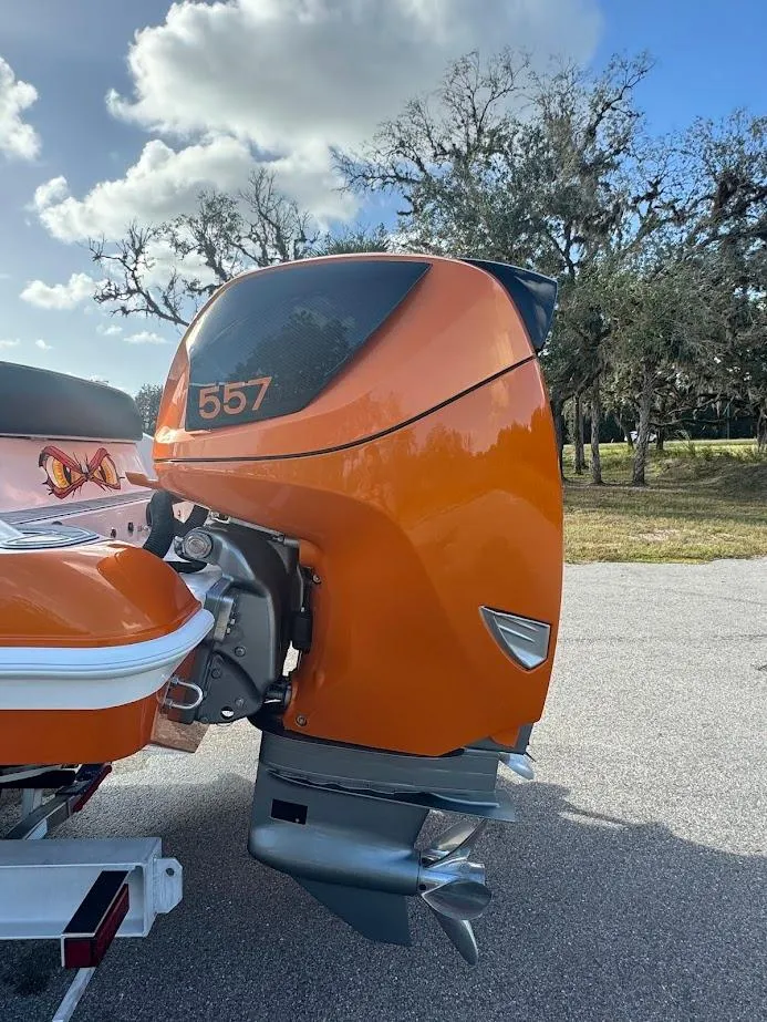 Slide: The Image of Orange 2015 Deep Impact 399 Cabin boat engine, parked outdoors under a cloudy sky. - 18