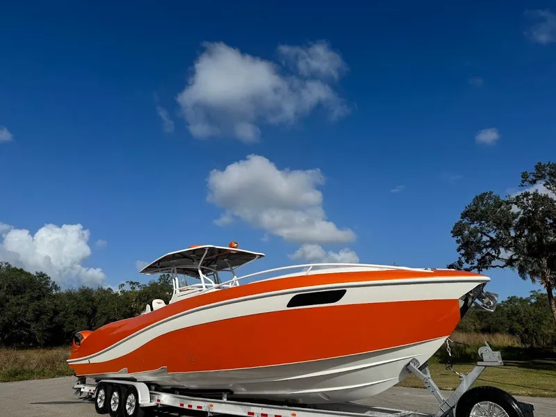 Slide: The Image of Orange 2015 Deep Impact 399 Cabin boat on trailer under blue sky. - 2