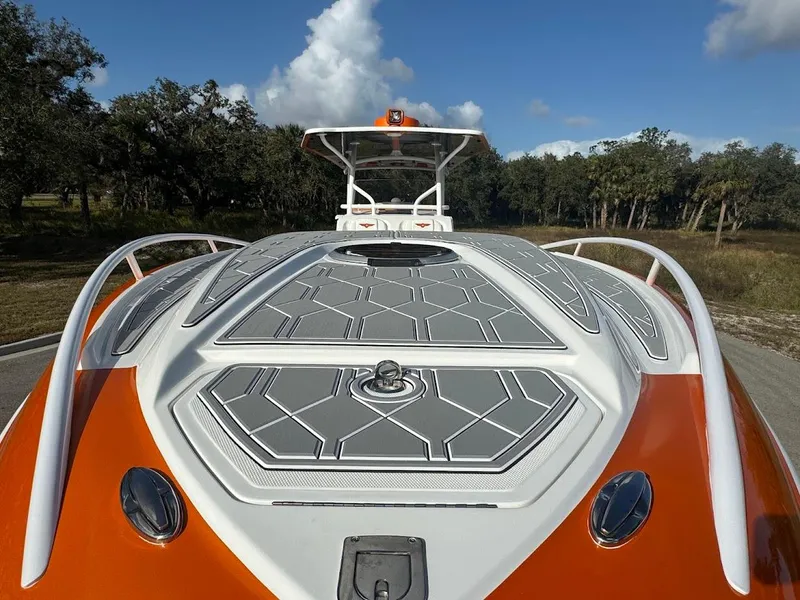 Slide: The Image of 2015 Deep Impact 399 Cabin boat with orange and gray deck, parked outdoors. - 23