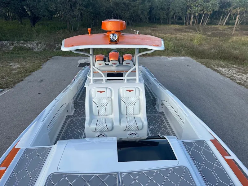 Slide: The Image of 2015 Deep Impact 399 Cabin boat with orange accents, docked on a paved path. - 29