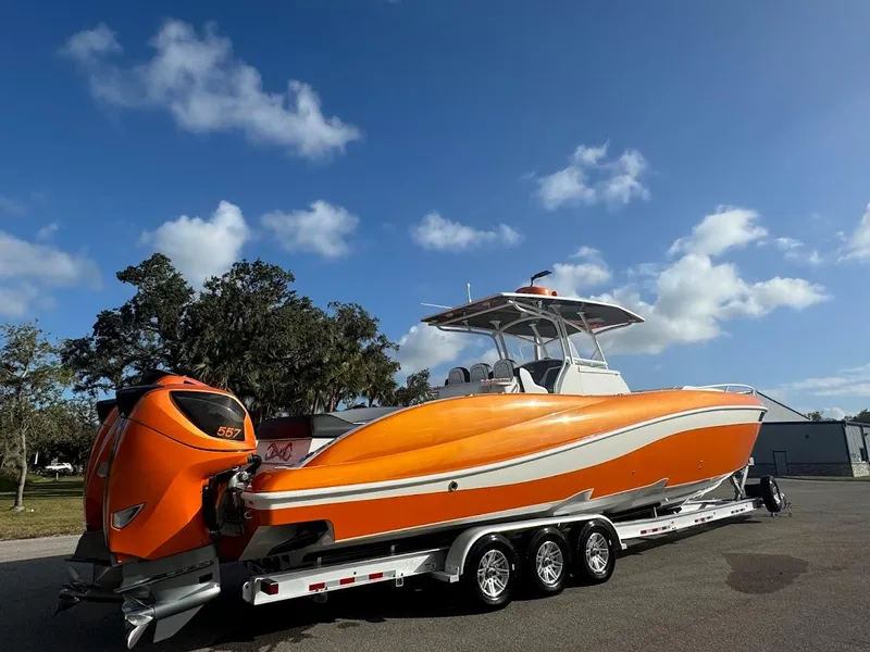 Slide: The Image of Orange 2015 Deep Impact 399 Cabin boat on trailer under blue sky. - 3