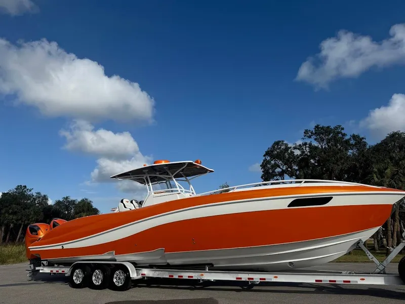 Slide: The Image of Orange 2015 Deep Impact 399 Cabin boat on trailer under blue sky. - 5