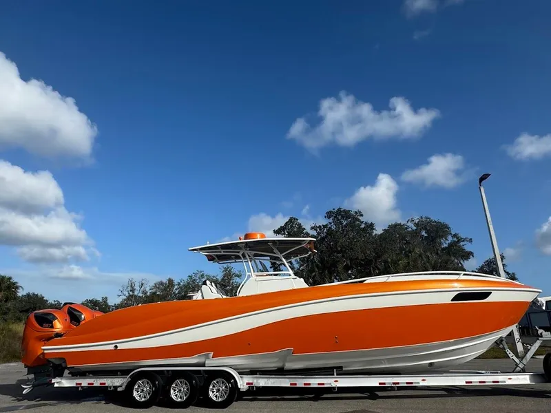 Slide: The Image of 2015 Deep Impact 399 Cabin boat in vibrant orange on a trailer under a clear blue sky. - 6