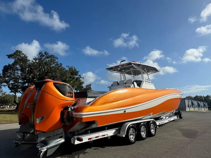 Slide: The Image of 2015 Deep Impact 399 Cabin boat in vibrant orange on a trailer under a clear blue sky. - 7