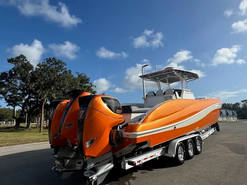 Slide: The Image of Orange 2015 Deep Impact 399 Cabin boat on trailer under blue sky. - 8