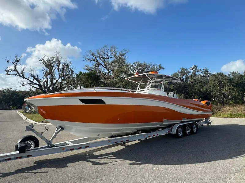 Slide: The Image of 2015 Deep Impact 399 Cabin boat on trailer, vibrant orange and white design, parked outdoors. - 9