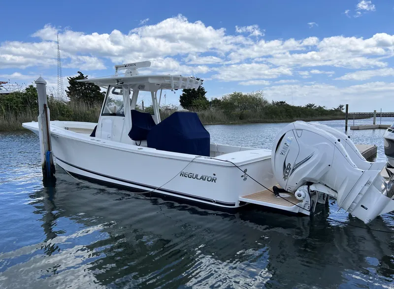 The Image of 2022 Regulator 31 boat docked on calm water under a partly cloudy sky. - 0
