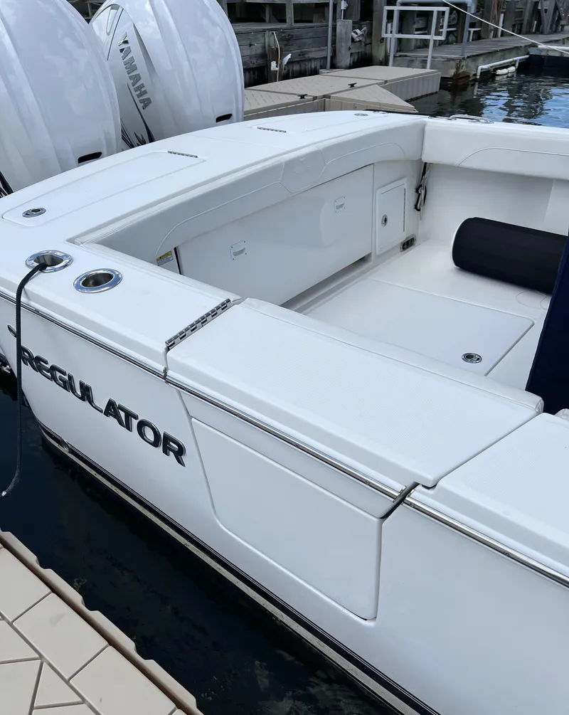Slide: The Image of 2022 Regulator 31 boat docked, showcasing sleek white design and spacious seating area. - 7