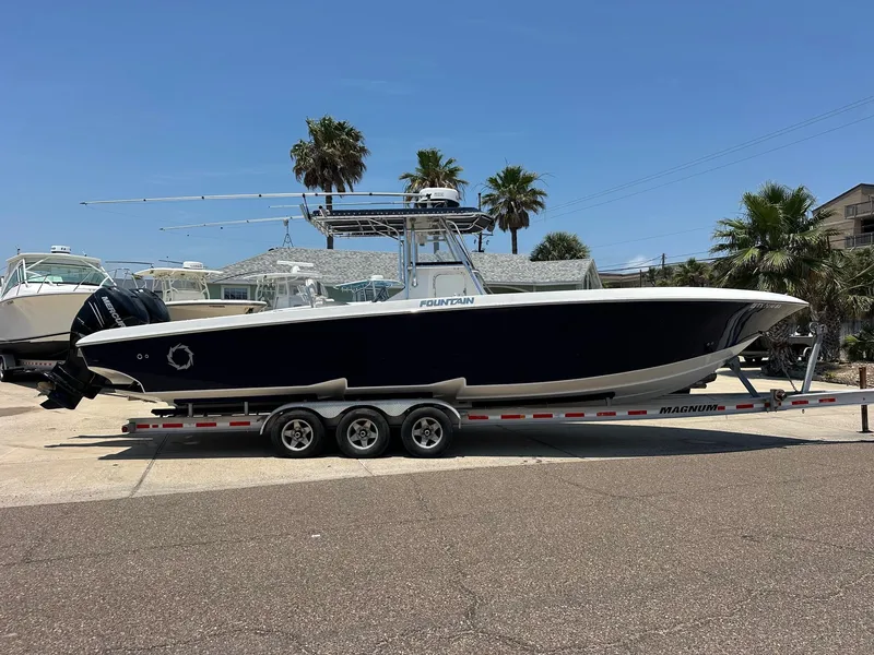 Slide: The Image of 2008 Fountain Center Console boat on a trailer, parked outdoors under a clear blue sky. - 1