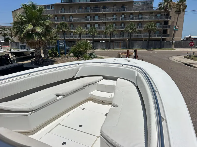 Slide: The Image of 2008 Fountain Center Console boat with white seating, docked near a building and palm trees. - 11
