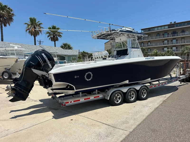 Slide: The Image of 2008 Fountain Center Console boat on trailer, parked outdoors near palm trees. - 2