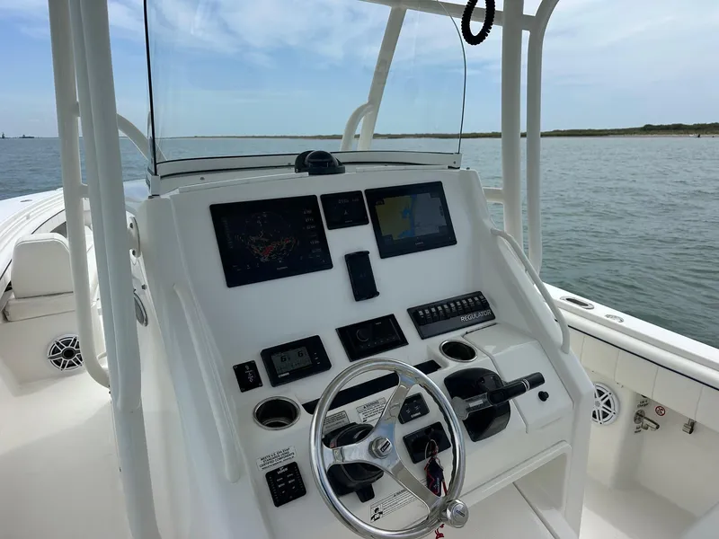 Slide: The Image of 2016 Regulator center console boat dashboard with navigation screens and steering wheel on open water. - 7