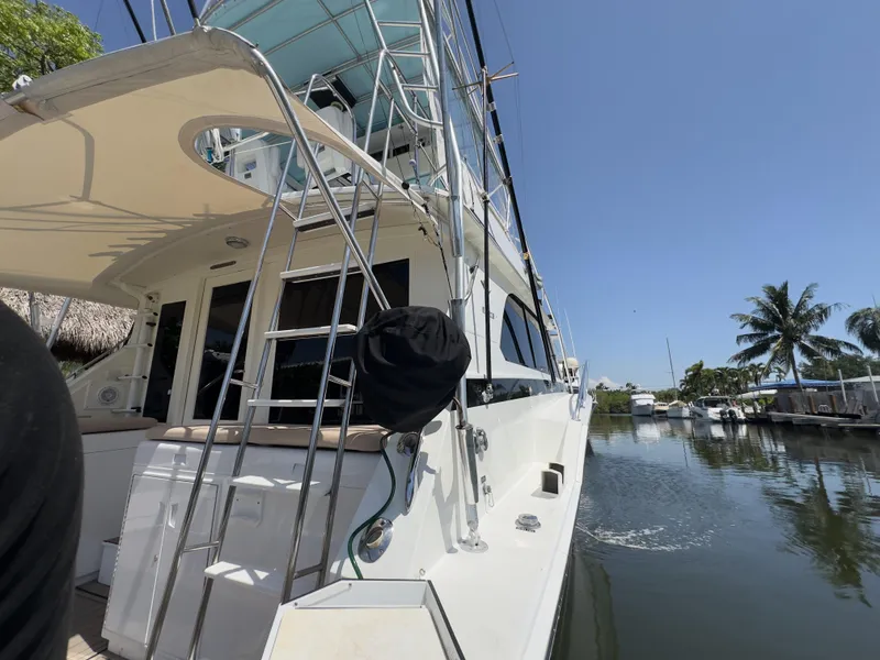 Slide: The Image of 1983 Bertram 46 Convertible yacht docked by a calm waterfront under clear blue skies. - 10