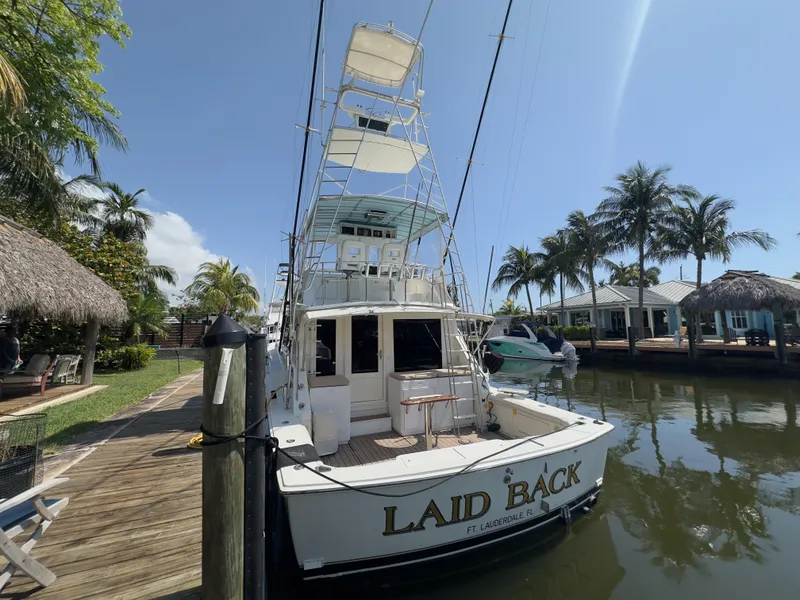 Slide: The Image of 1983 Bertram 46 Convertible yacht docked, named "Laid Back," surrounded by palm trees. - 5