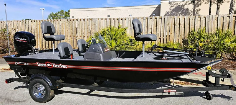 Slide: The Image of 2025 Tracker Bass Tracker Classic XL boat on trailer, black with red accents, parked outdoors. - 7
