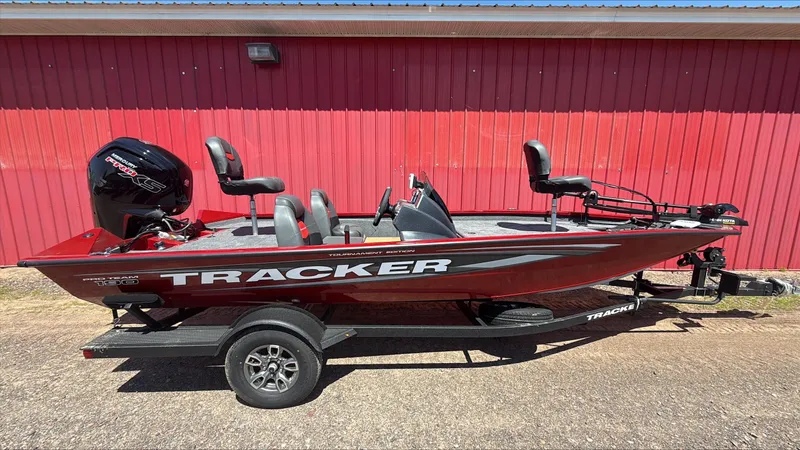 The Image of 2025 Tracker Pro Team 190 boat on trailer, red exterior, parked by red building. - 0