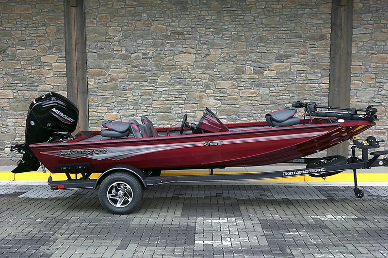 The Image of 2025 Ranger RT178 boat in red, parked on a trailer against a stone wall. - 0