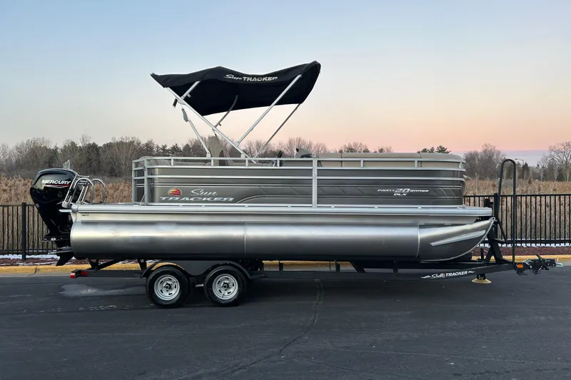 The Image of 2025 Sun Tracker Party Barge 20 DLX pontoon boat on trailer at sunset. - 0