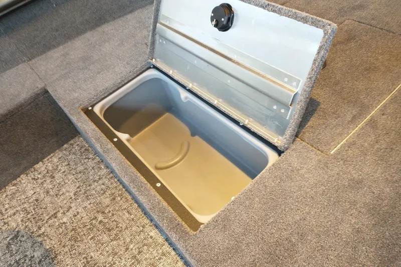 Slide: The Image of Open storage compartment in 2025 Tracker Super Guide V-16 T boat, featuring carpeted interior. - 13